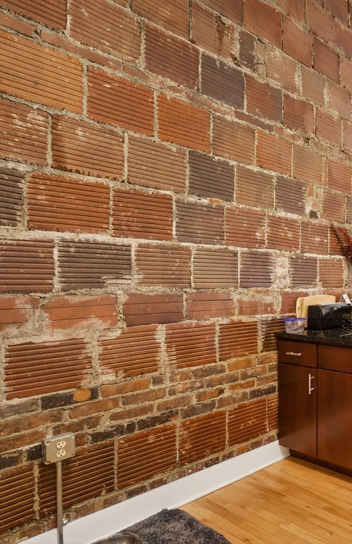 Original exposed red brick wall running the length of a kitchen, with pendant lights
