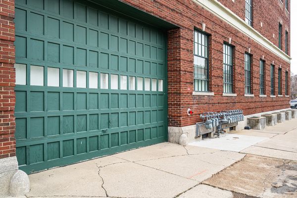 The building's green paneled garage door, the entrance to indoor parking, set in the red brick side wall