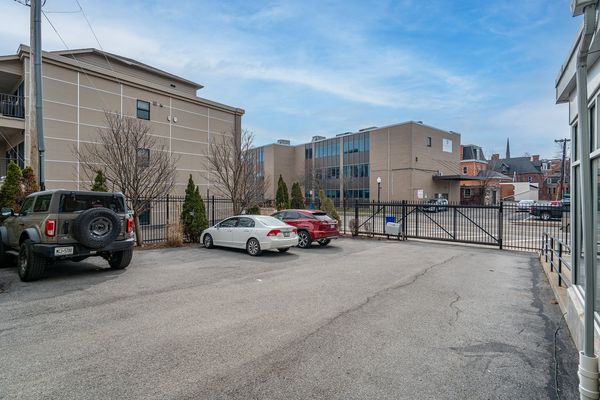 The gated off-street parking lot behind the building, with an iron fence and gate