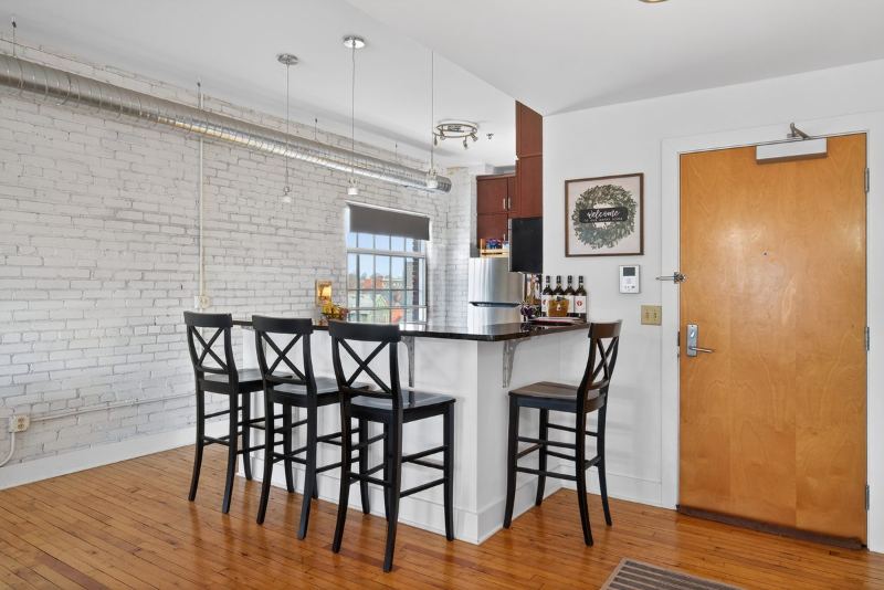 Breakfast bar with four stools beside a white-painted brick wall