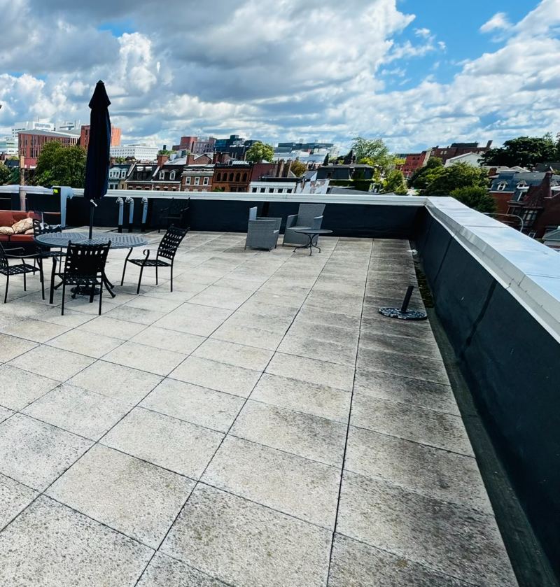 The rooftop terrace with an outdoor dining table and chairs, lounge chairs, and the city beyond